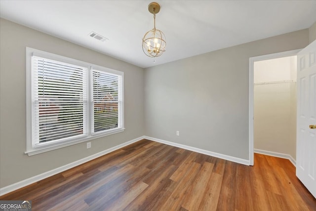 empty room featuring hardwood / wood-style floors and a chandelier