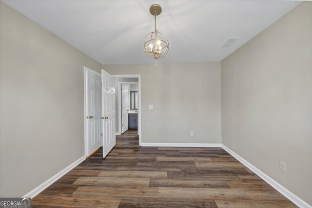 empty room with dark hardwood / wood-style floors and a chandelier