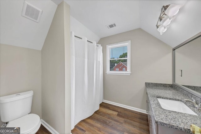 bathroom with hardwood / wood-style flooring, vanity, toilet, and vaulted ceiling