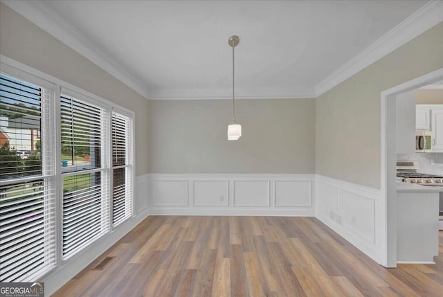 unfurnished dining area with light wood-type flooring and crown molding