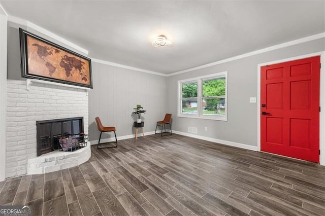 living area featuring dark hardwood / wood-style flooring, ornamental molding, and a brick fireplace