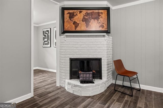 interior space with crown molding, hardwood / wood-style floors, wood walls, and a brick fireplace