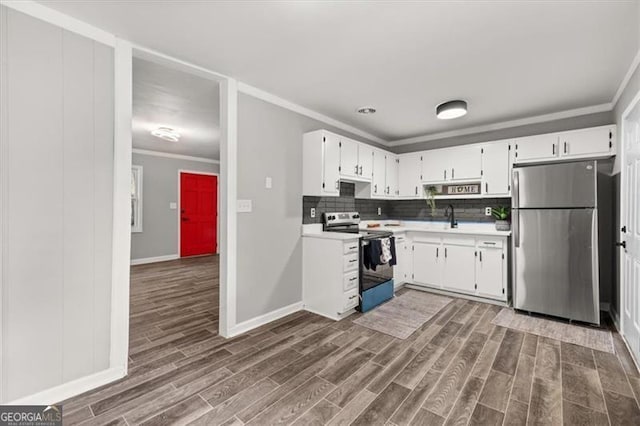 kitchen with appliances with stainless steel finishes, dark hardwood / wood-style flooring, backsplash, sink, and white cabinets