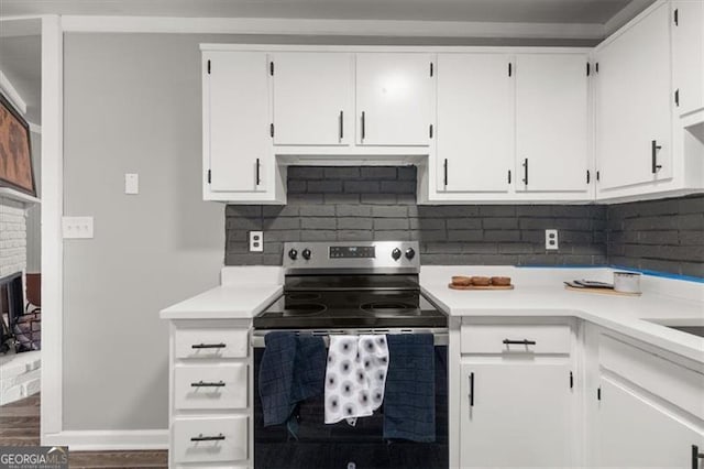 kitchen with decorative backsplash, a fireplace, stainless steel electric stove, white cabinets, and dark hardwood / wood-style floors