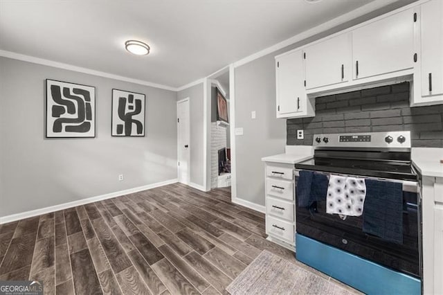 kitchen featuring stainless steel electric range, dark wood-type flooring, white cabinets, ornamental molding, and tasteful backsplash