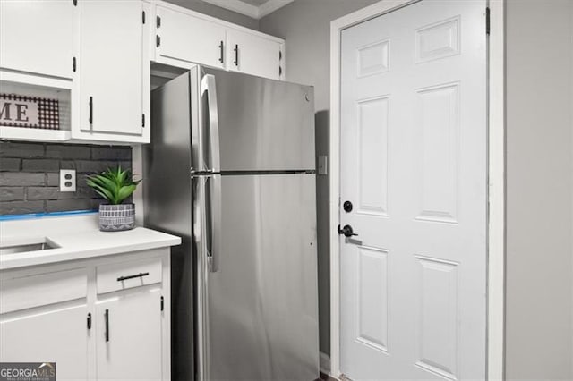 kitchen featuring white cabinets, stainless steel fridge, and backsplash