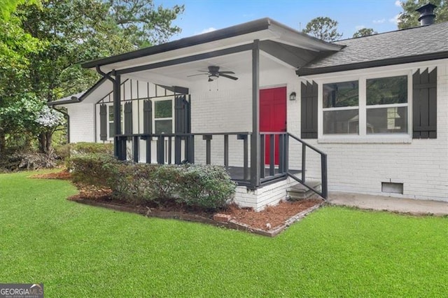 view of exterior entry featuring ceiling fan and a lawn