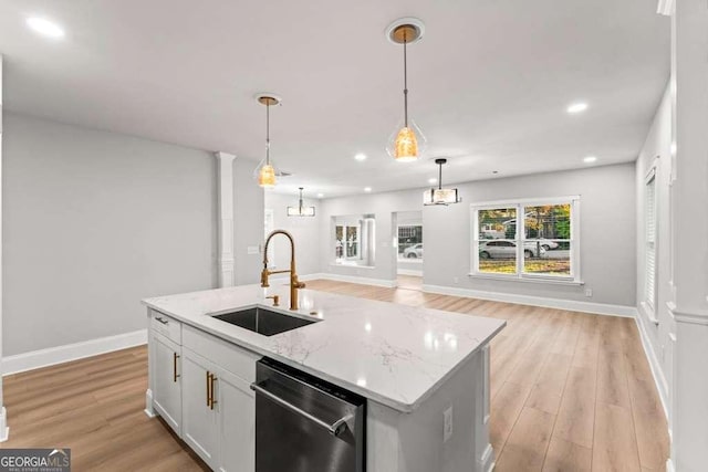 kitchen with sink, stainless steel dishwasher, an island with sink, pendant lighting, and light hardwood / wood-style floors