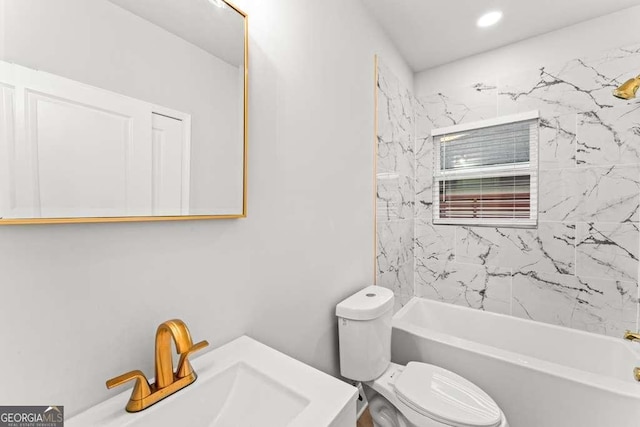 full bathroom featuring tiled shower / bath combo, toilet, and sink