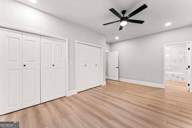 unfurnished bedroom featuring two closets, light hardwood / wood-style flooring, and ceiling fan