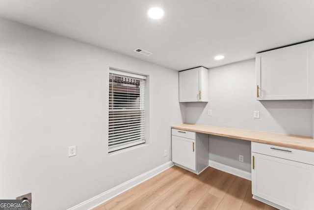 unfurnished office featuring light wood-type flooring and built in desk