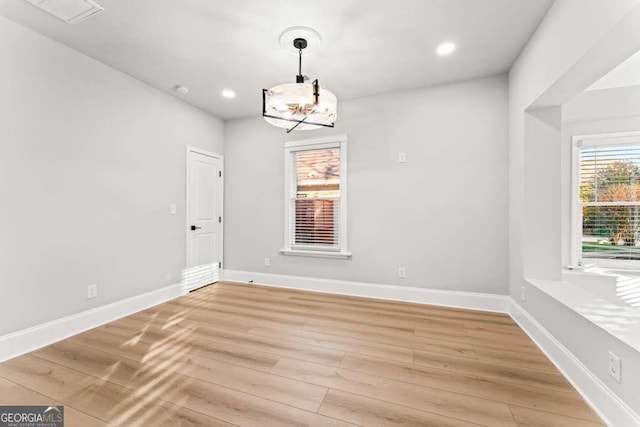 empty room featuring light wood-type flooring and an inviting chandelier