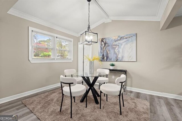 dining area featuring a chandelier, hardwood / wood-style flooring, vaulted ceiling, and ornamental molding