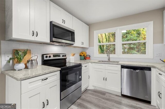 kitchen featuring white cabinets, sink, stainless steel appliances, and light hardwood / wood-style flooring