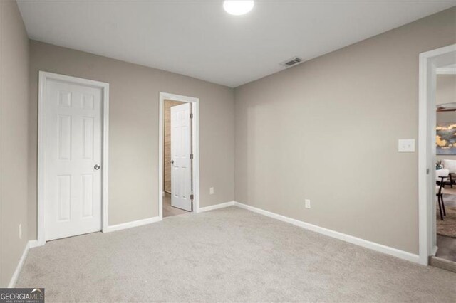 unfurnished bedroom featuring connected bathroom and light colored carpet