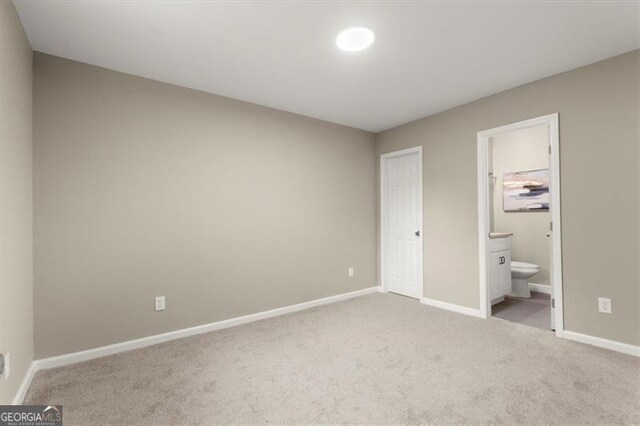 unfurnished bedroom featuring connected bathroom, light carpet, and a closet