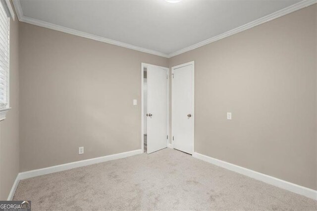 empty room featuring plenty of natural light, crown molding, and light carpet