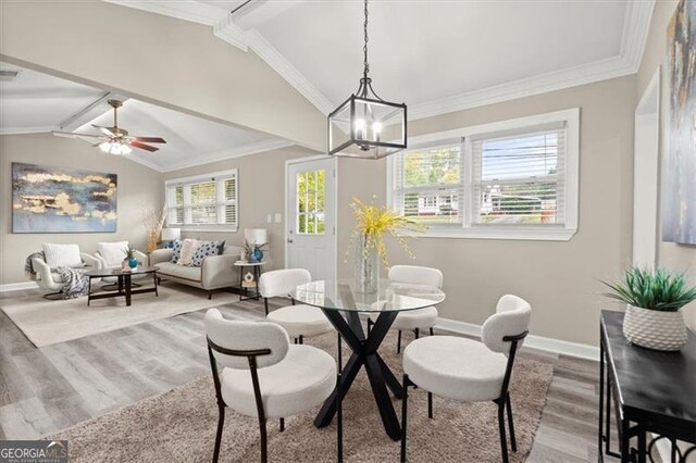 dining space with ornamental molding, a healthy amount of sunlight, vaulted ceiling, and hardwood / wood-style flooring