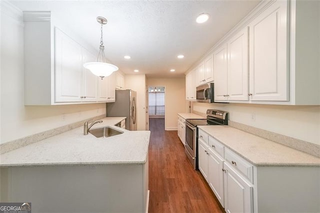 kitchen featuring dark wood-type flooring, sink, hanging light fixtures, white cabinetry, and stainless steel appliances