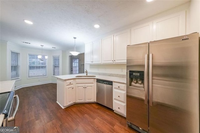 kitchen with kitchen peninsula, appliances with stainless steel finishes, dark wood-type flooring, pendant lighting, and white cabinetry