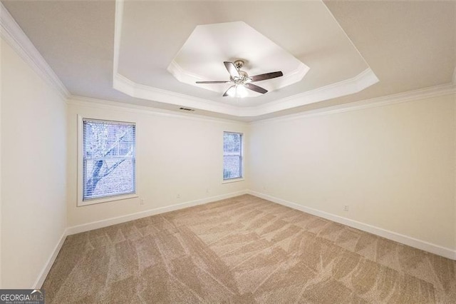 carpeted empty room featuring a tray ceiling, ceiling fan, and ornamental molding