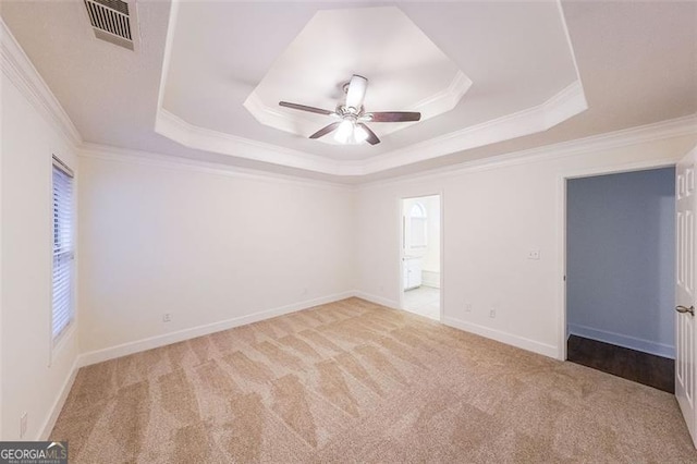 carpeted empty room featuring a tray ceiling, ceiling fan, and crown molding