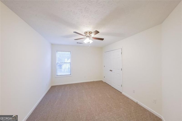 carpeted empty room featuring ceiling fan and a textured ceiling