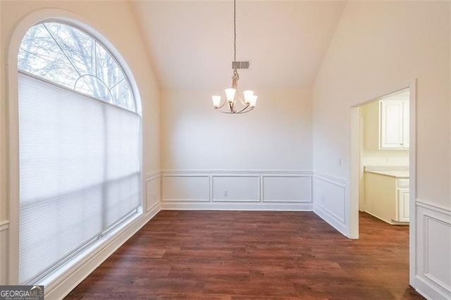 unfurnished dining area featuring lofted ceiling, dark wood-type flooring, and an inviting chandelier