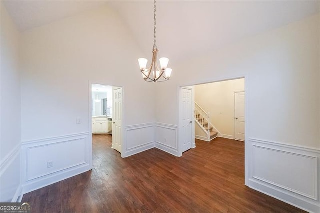 unfurnished dining area featuring a chandelier, dark hardwood / wood-style flooring, and high vaulted ceiling