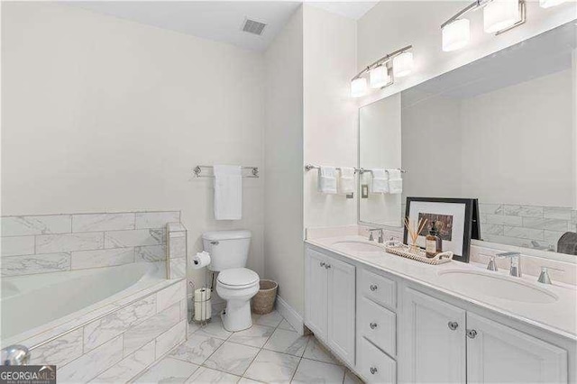 bathroom featuring tiled tub, vanity, and toilet