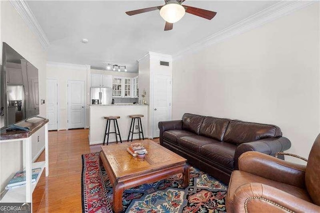 living room featuring ceiling fan, crown molding, and light hardwood / wood-style flooring