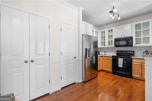 kitchen with white cabinets, hardwood / wood-style flooring, tasteful backsplash, and black appliances