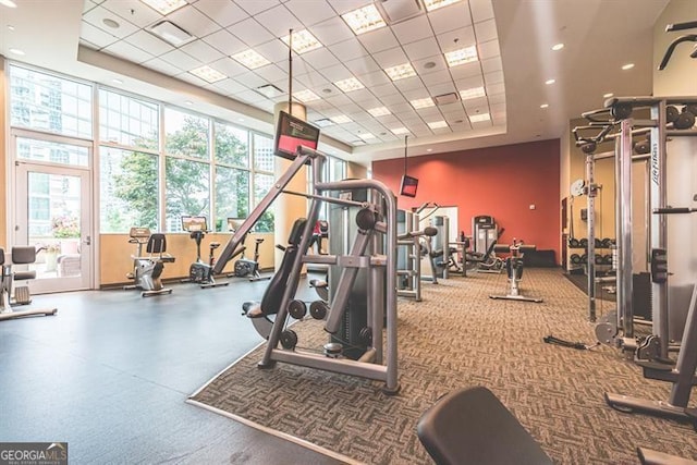 gym featuring a raised ceiling, plenty of natural light, and a drop ceiling