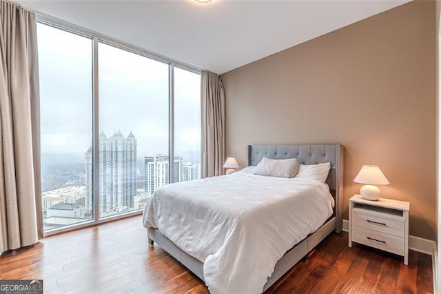 bedroom featuring access to outside, dark wood-type flooring, and a wall of windows