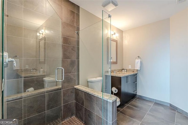 bathroom with tile patterned floors, vanity, a shower with shower door, and toilet