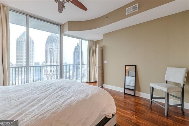 bedroom with floor to ceiling windows, dark hardwood / wood-style flooring, access to outside, and ceiling fan