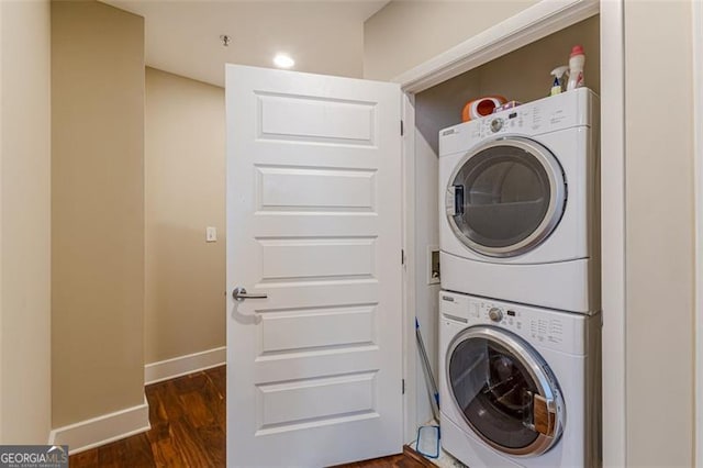 laundry room featuring dark hardwood / wood-style flooring and stacked washing maching and dryer