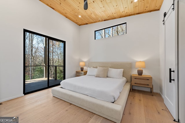 bedroom featuring light wood-type flooring, access to outside, vaulted ceiling, a barn door, and wooden ceiling