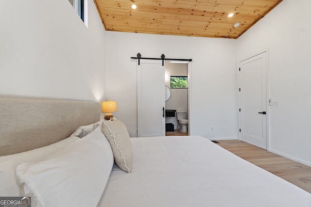 bedroom with a barn door, ensuite bathroom, wooden ceiling, and hardwood / wood-style flooring