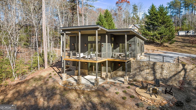 rear view of property featuring a patio, a fire pit, and a deck