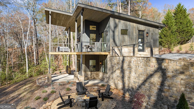 rear view of property featuring an outdoor fire pit and a patio area