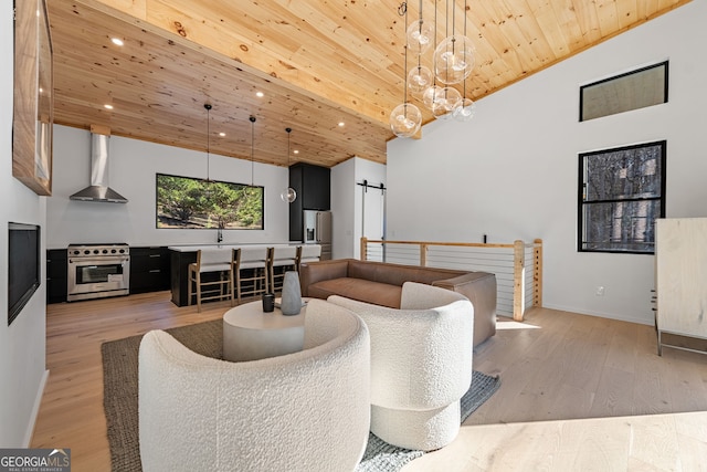 living room featuring a high ceiling, light wood-type flooring, a barn door, and wood ceiling