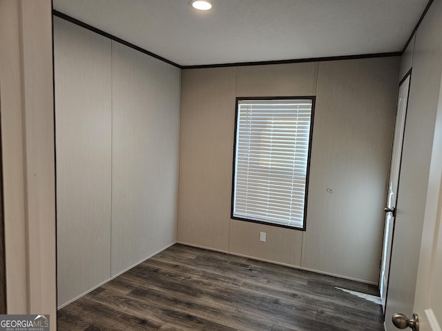 empty room with dark hardwood / wood-style floors and ornamental molding