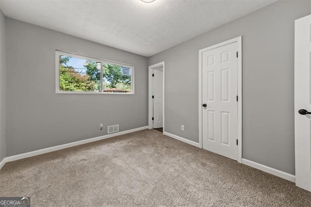 unfurnished bedroom with a textured ceiling and light carpet