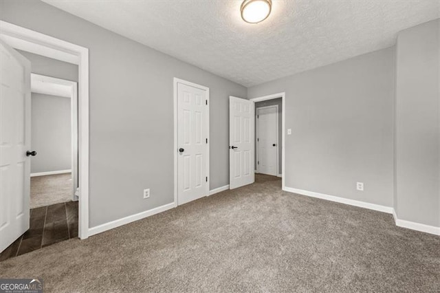 unfurnished bedroom featuring a textured ceiling and dark colored carpet