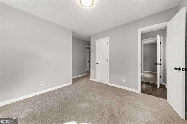 unfurnished bedroom featuring a textured ceiling, a closet, and dark carpet