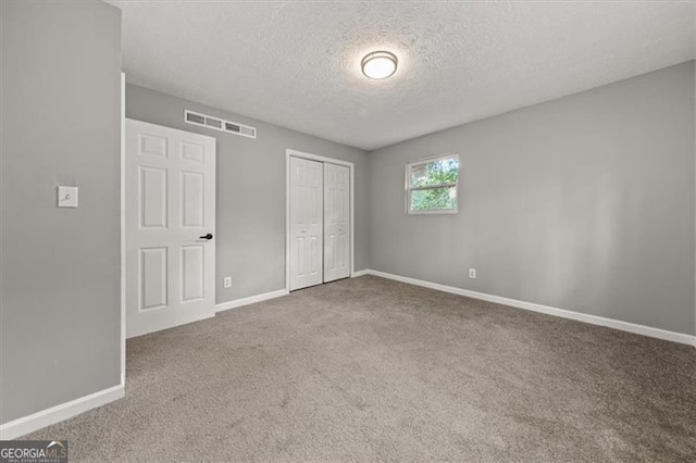 unfurnished bedroom with carpet flooring, a closet, and a textured ceiling