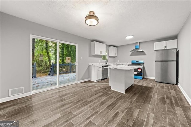 kitchen featuring wall chimney exhaust hood, dark hardwood / wood-style floors, a center island, white cabinets, and appliances with stainless steel finishes