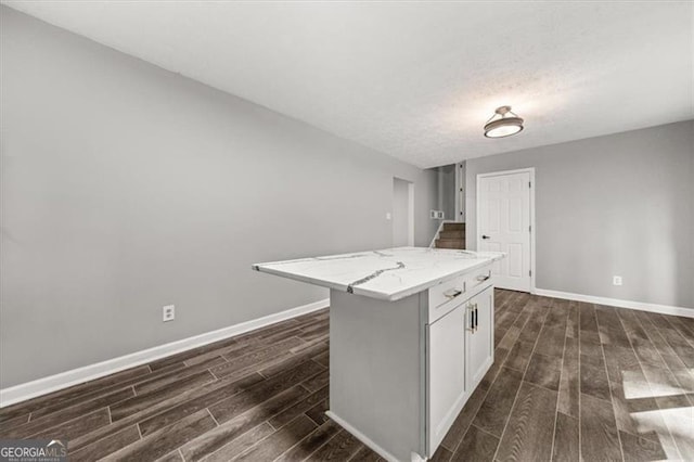 kitchen featuring a center island, a textured ceiling, white cabinetry, and light stone countertops