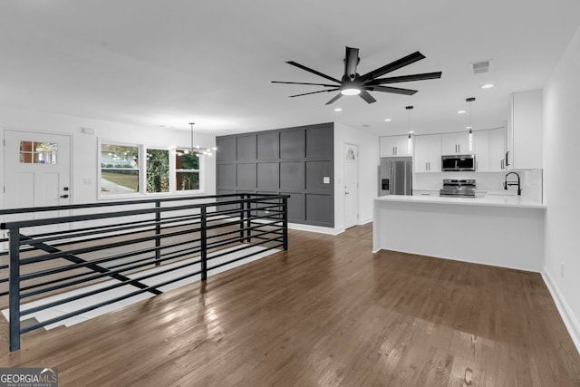 unfurnished living room featuring dark hardwood / wood-style floors, sink, and ceiling fan with notable chandelier